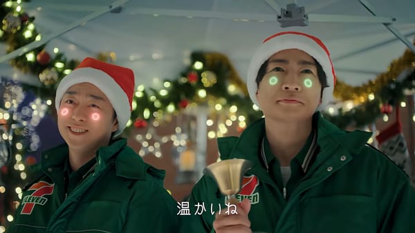 櫻井翔與相葉雅紀穿著 7-Eleven 制服與聖誕帽飾演外星人店員。兩人臉頰上有發光圓圈，背景是聖誕裝飾，日文字幕顯示「好溫暖啊」。